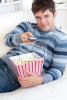 entspannter-junger-mann-popcorn-essen-und-mit-einer-fernbedienung-liegend-auf-t-400-32997.jpg